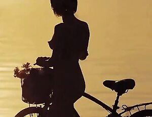 Naked babe walking her bike on the beach